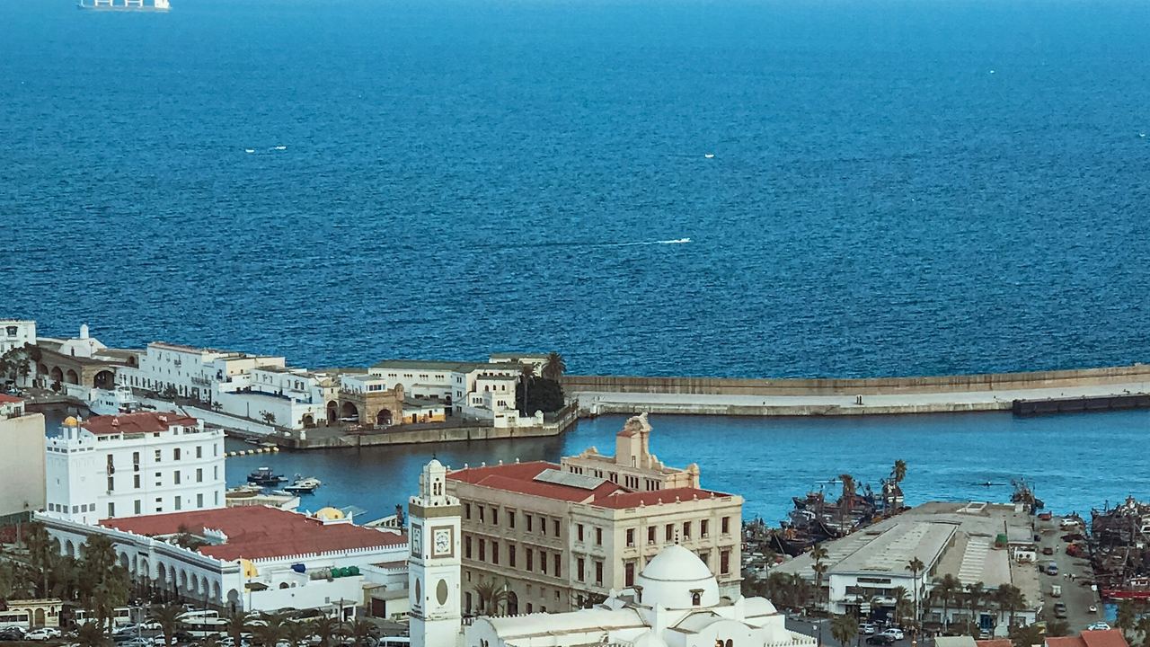 The white buildings of Algiers above its harbour and the deep blue bay