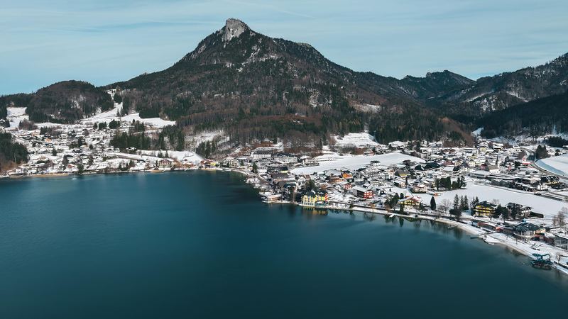 Fuschl am See in winter, its houses in snow along the dark blue lake below the Schober