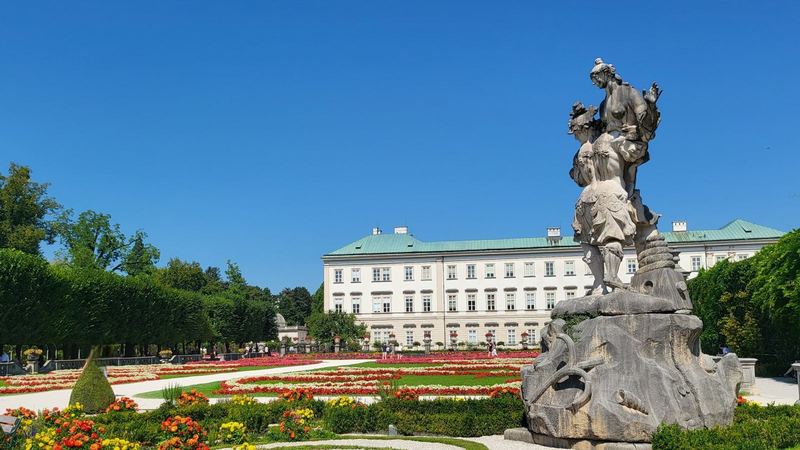 The flower beds and baroque statues of the Mirabell Gardens, Salzburg, under a blue sky
