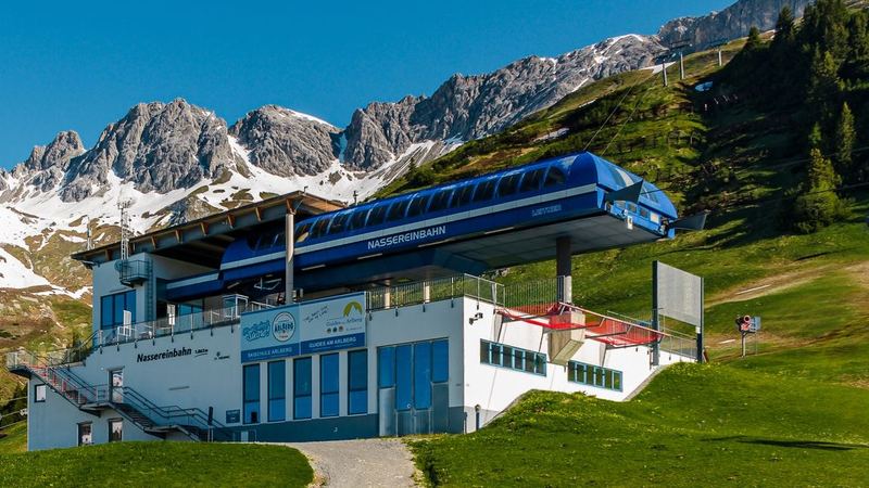 The blue Nasserein gondola station of St. Anton below the jagged Arlberg peaks in early summer