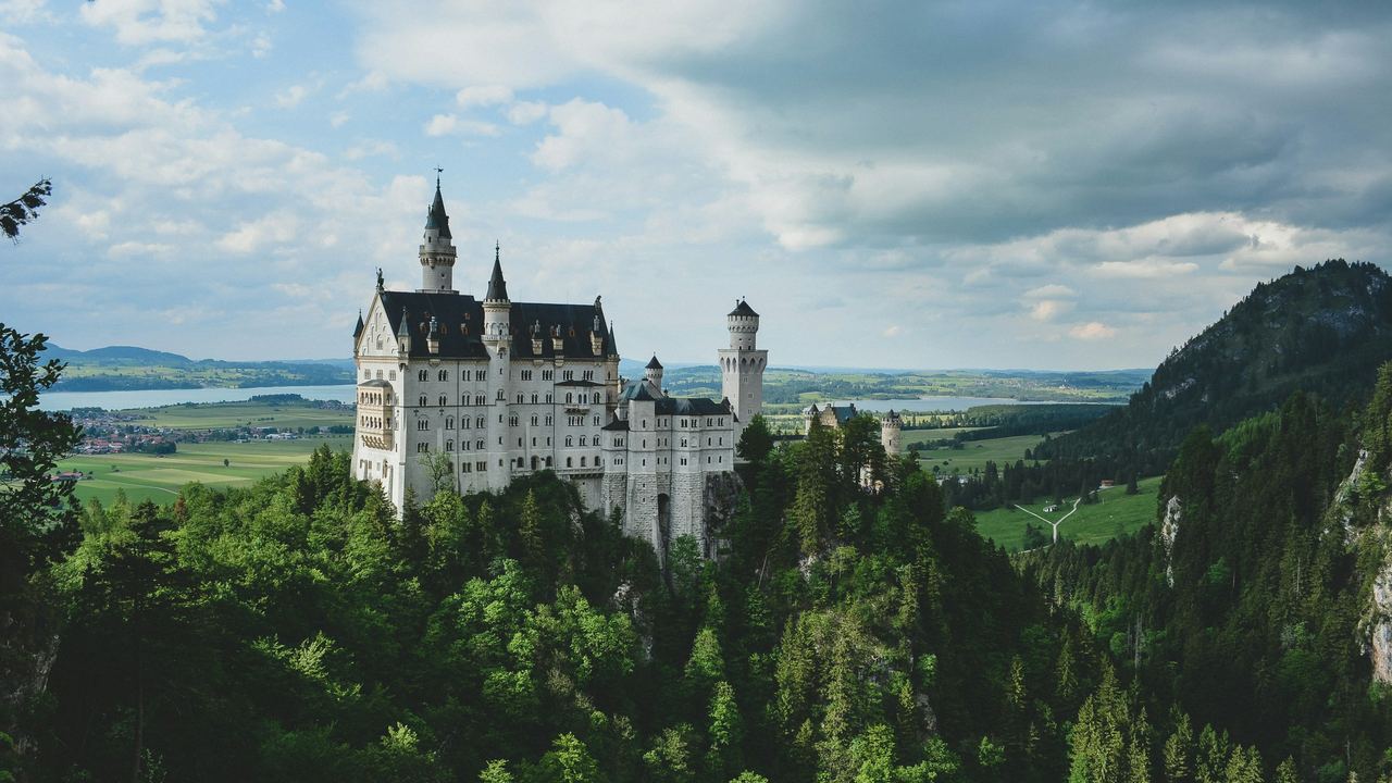 Neuschwanstein Castle above the forest and the green fields of the Allgäu