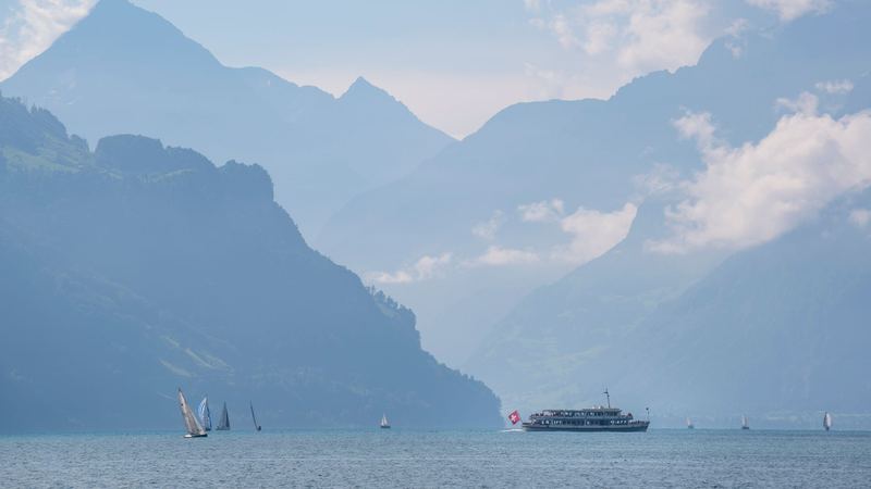 Sailing boats and a lake steamer on Lake Lucerne below the mountains