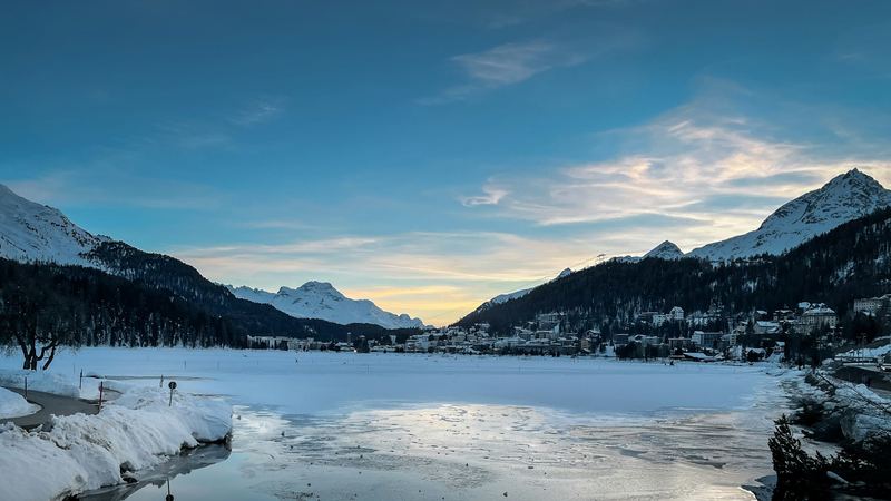 The frozen lake of St. Moritz in winter, with the town and the Engadine peaks at sunset