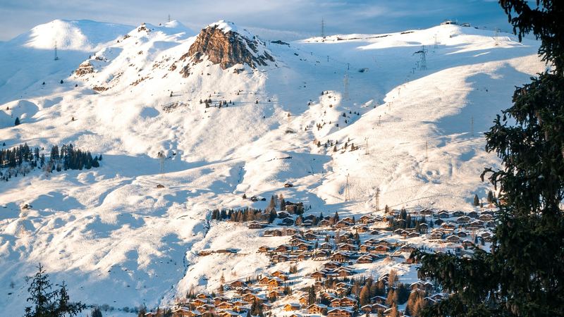 The chalets of Verbier in late sun below the snowfields of the ski area