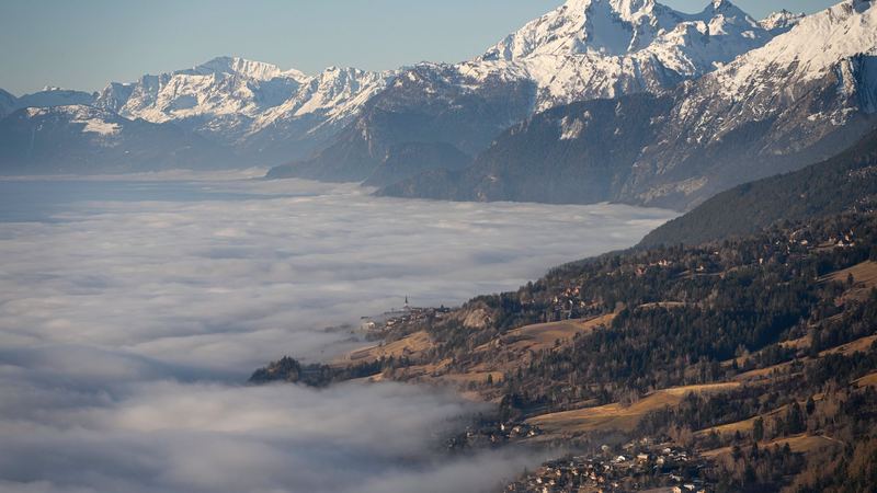 A sea of cloud filling the Rhône valley, with villages on the slopes below snow-covered peaks
