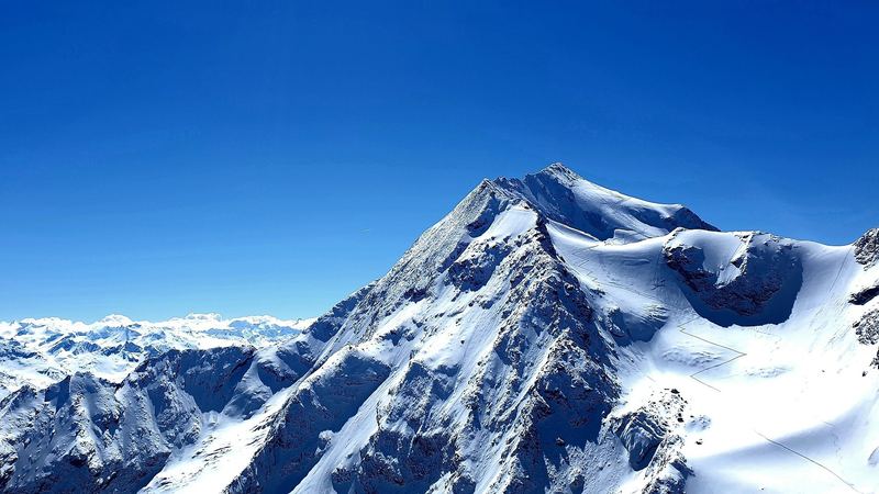 A great snow-covered peak against a deep blue sky above the Three Valleys
