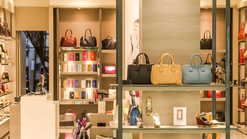 Leather handbags, purses and shoes on lit shelves in a boutique