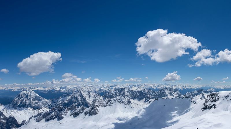 The snowfields of the Zugspitze and a sea of Alpine peaks under a deep blue sky