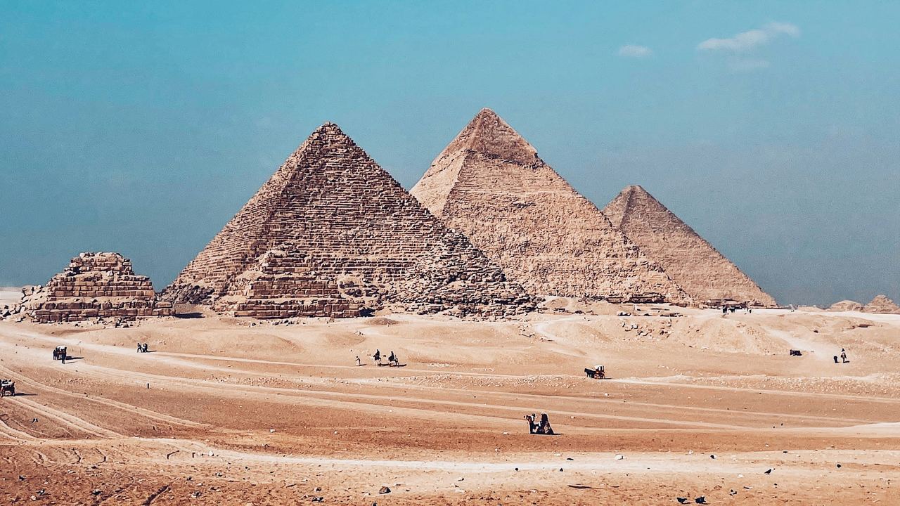 The Pyramids of Giza rising from the desert under a clear blue sky