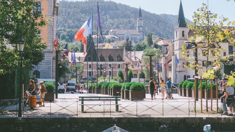 Flags, church spires and boats on the canal in the old town of Annecy, in summer