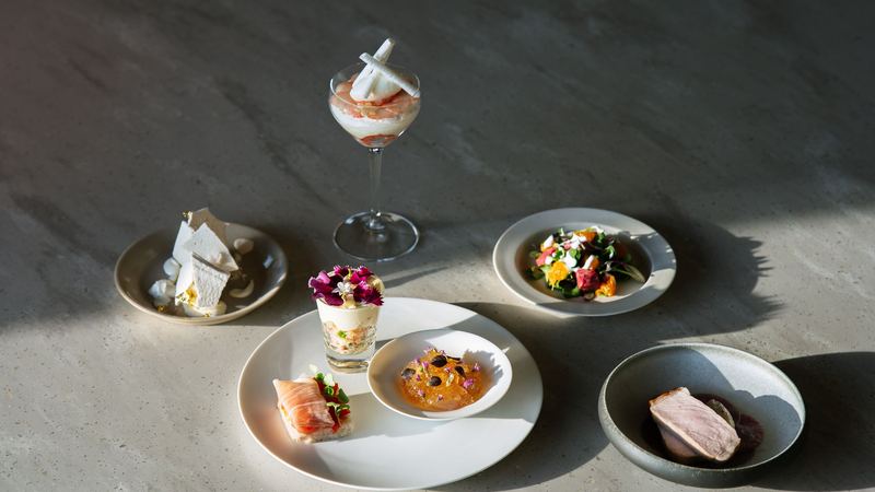 A tasting menu laid out on a stone table: small plates, flowers and a glass