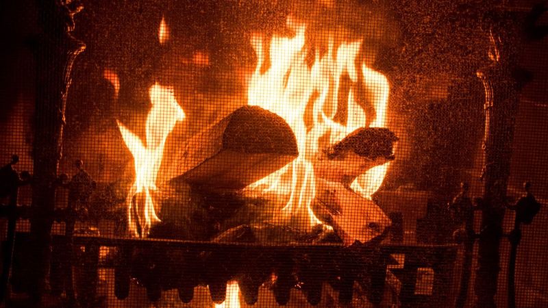 A log fire burning bright behind an ornate iron fire screen