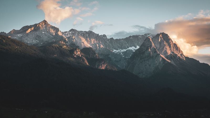 The Alpspitze and the Wetterstein range lit pink by the last sun above the dark forest