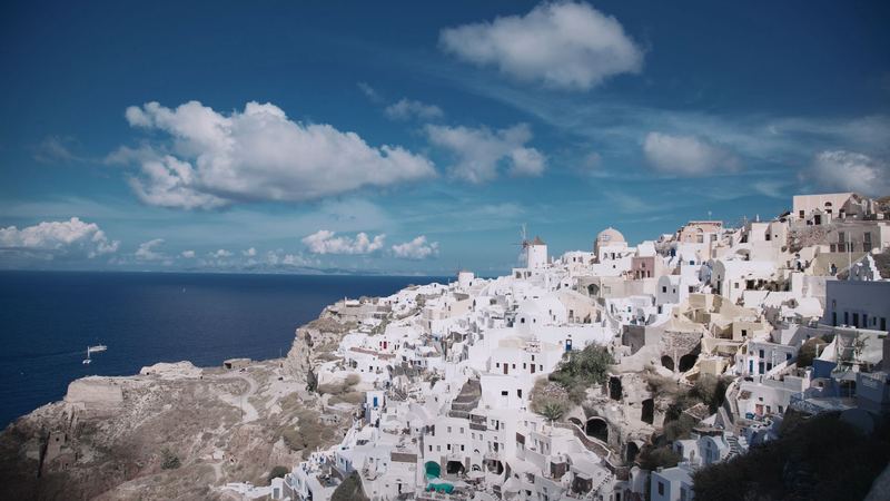 The white houses and windmills of Oia on the cliffs of Santorini above a deep blue Aegean
