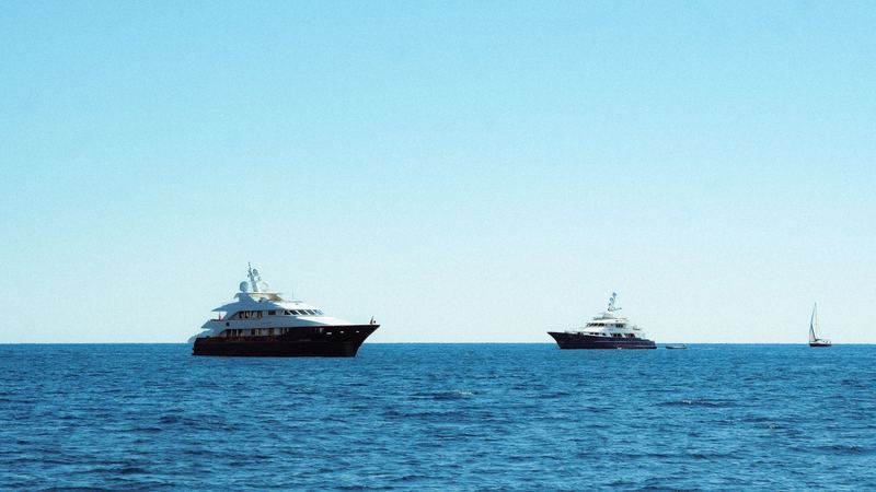 Two superyachts at anchor on a calm blue Adriatic Sea