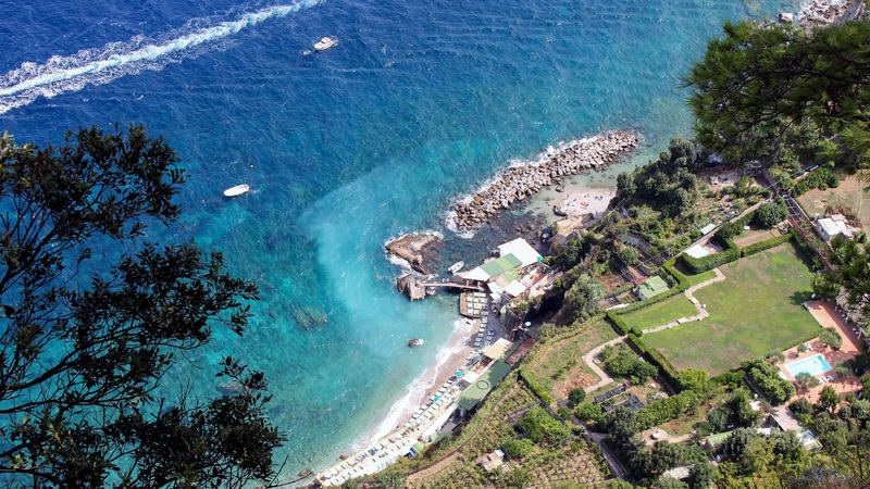 Deep blue and turquoise sea below the cliffs and gardens of Capri, seen from above