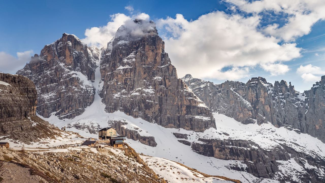 A mountain refuge below great walls of pale rock