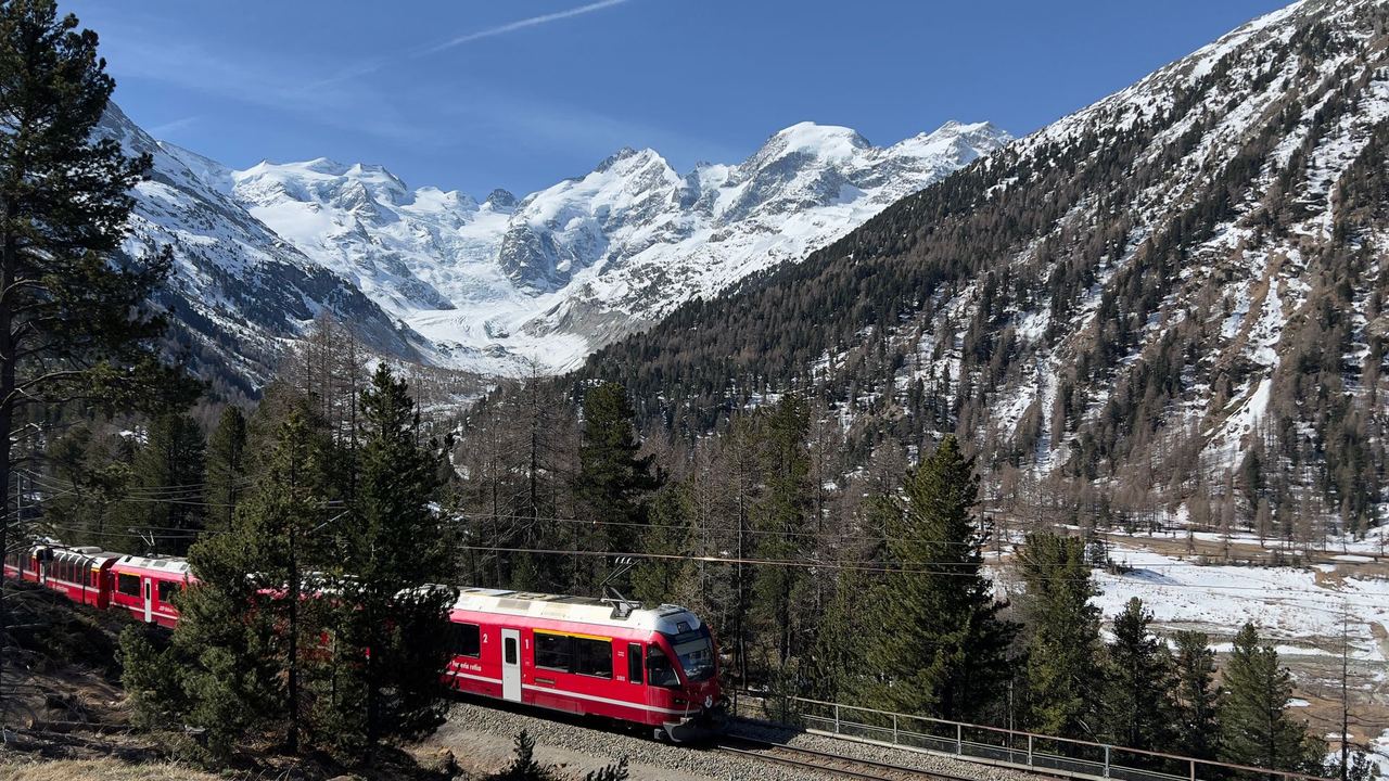 A red Rhaetian Railway train below the Bernina glaciers