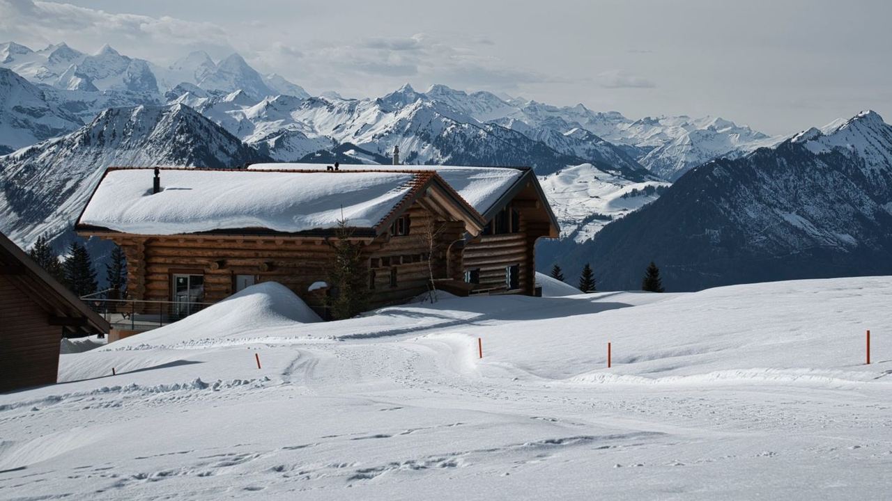 A log chalet in deep snow facing the peaks