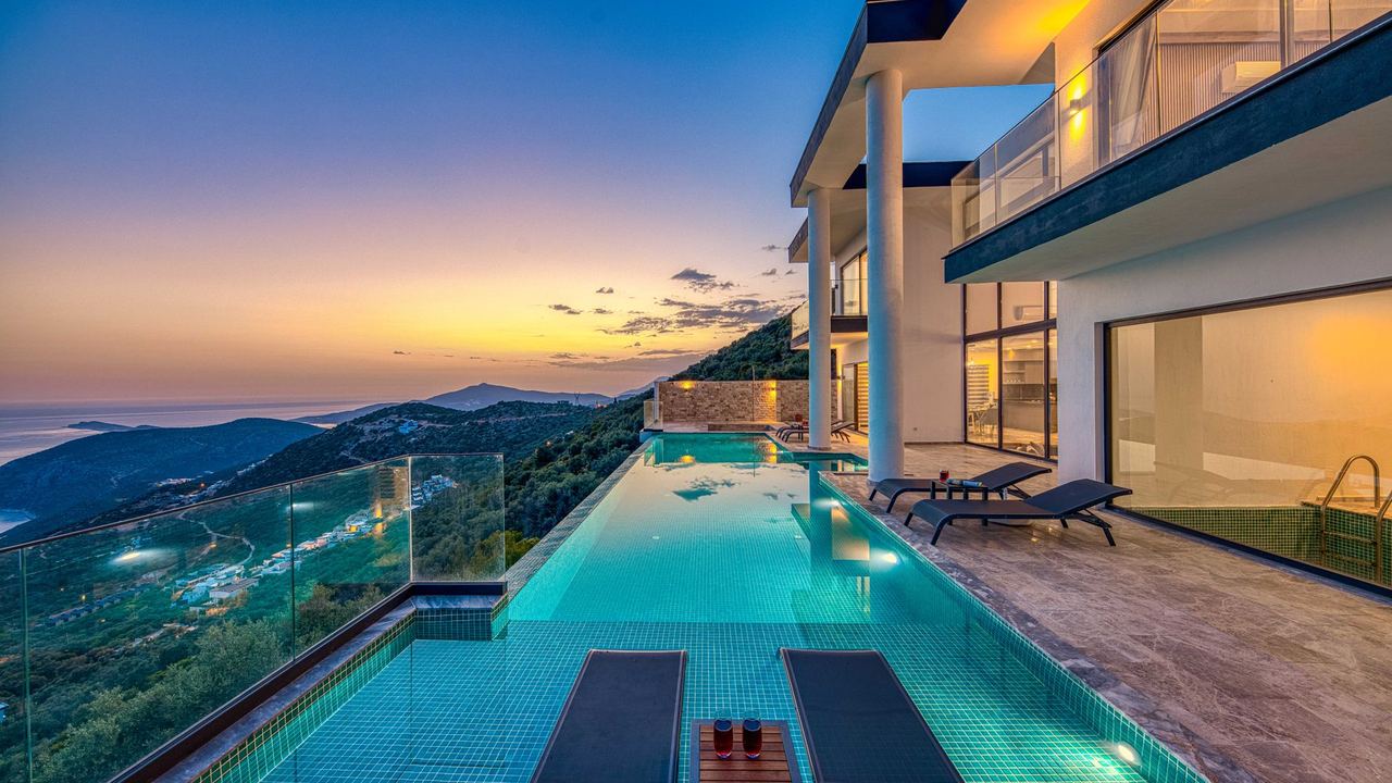 A villa and infinity pool over the sea at sunset