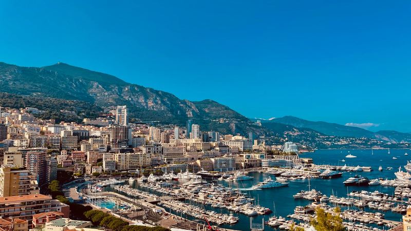 The towers and terraces of Monte-Carlo above Port Hercule under a clear blue sky