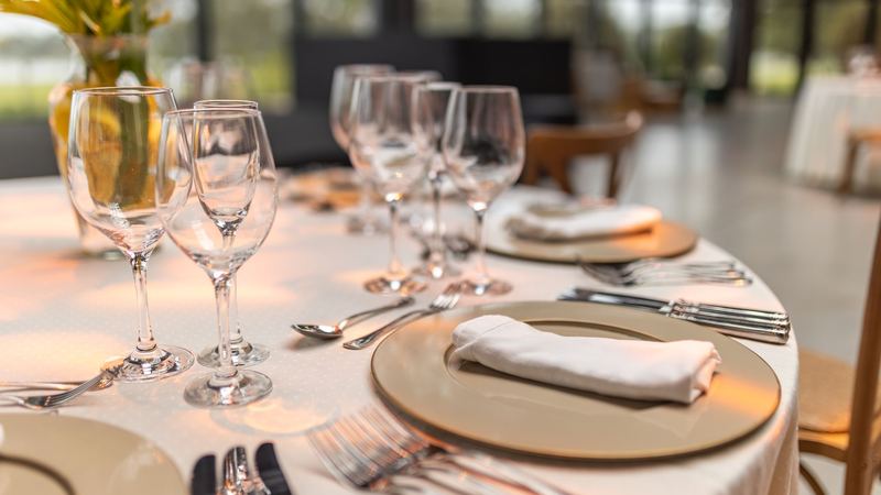 A table laid with gold chargers, folded white napkins, silver and crystal glasses