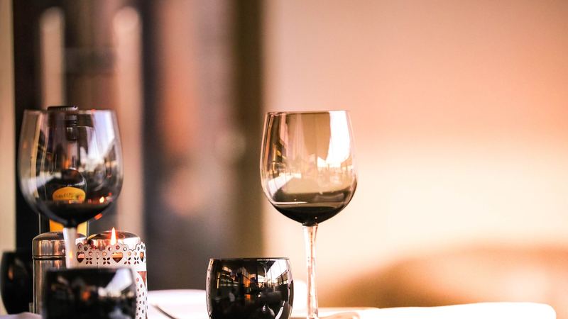 Glasses of red wine and a candle on a restaurant table in warm evening light