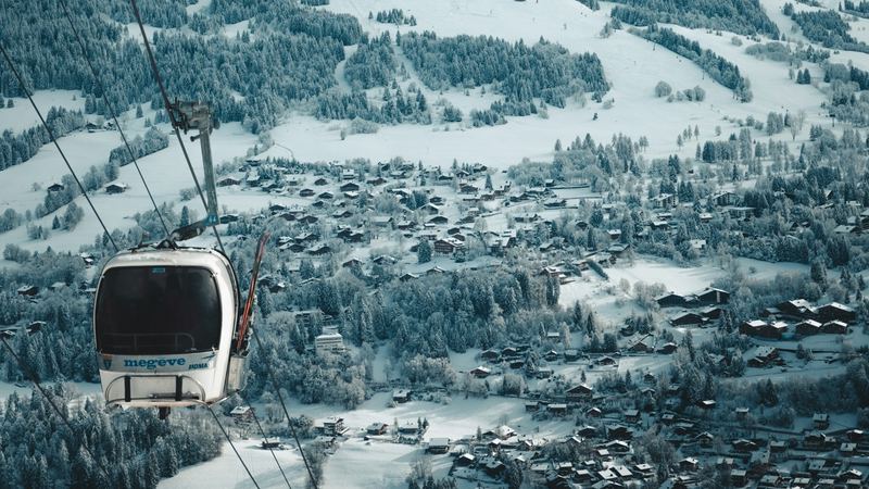 A Megève gondola cabin passing high above the snowy village and its chalets