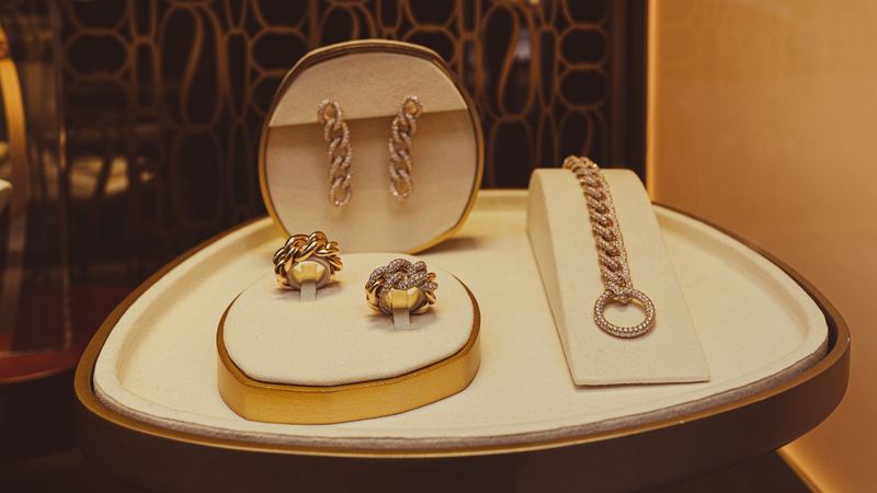 Gold and diamond chain earrings, rings and a bracelet on a cream display in a jeweller’s window