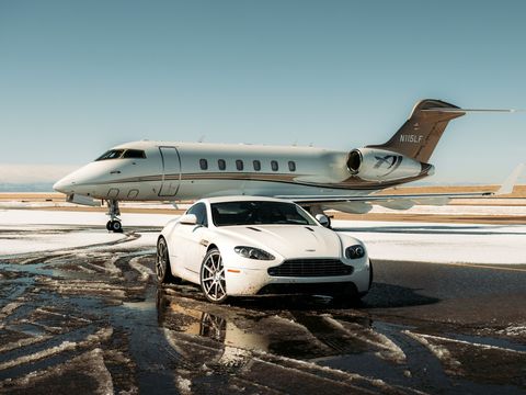A white Aston Martin Vantage beside a private jet