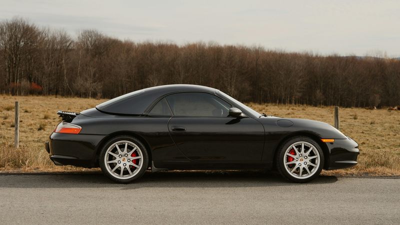 A black Porsche 911 of the 996 generation on a country road