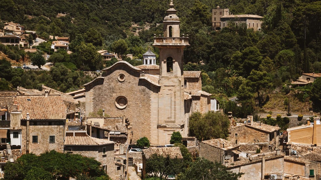 The church tower of Valldemossa and its stone village below the Tramuntana mountains
