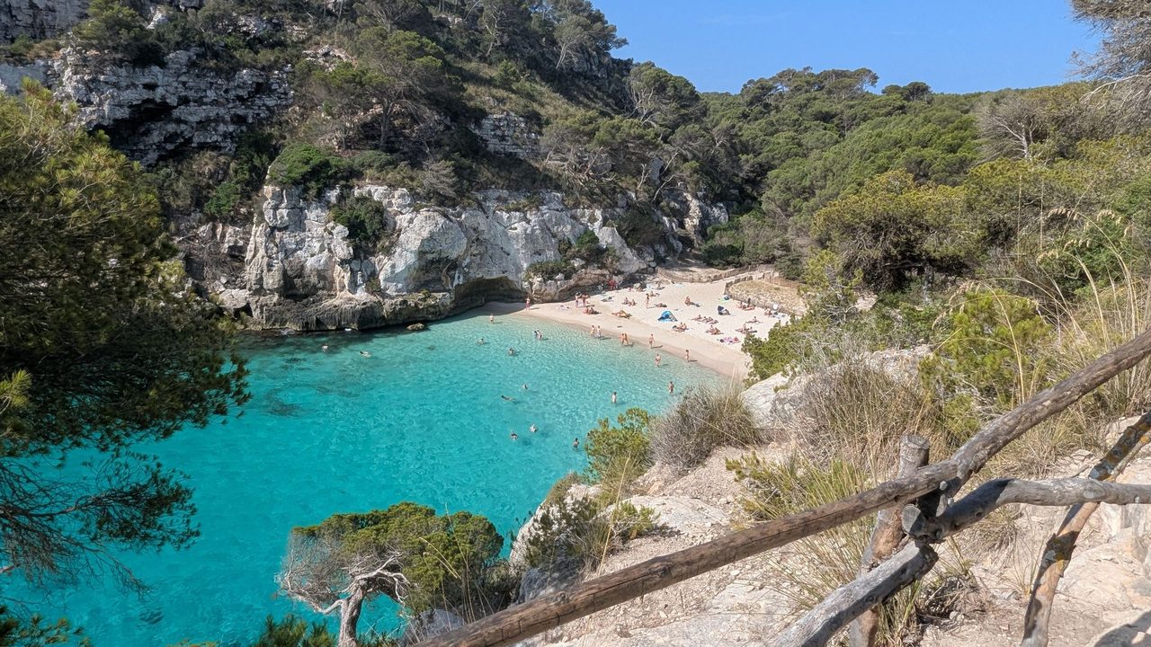 Turquoise water in the cove of Cala Macarella, ringed by pines and white cliffs