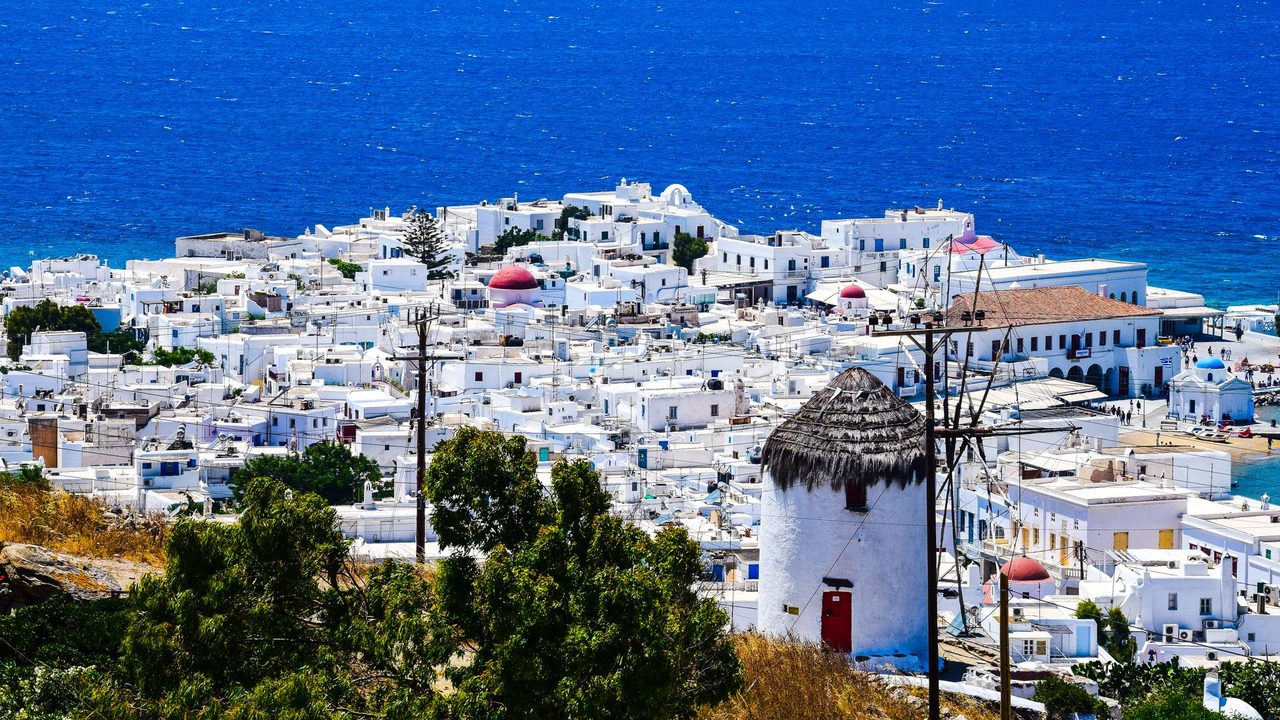 The white town of Mykonos, its domed chapels and a windmill above the deep blue Aegean