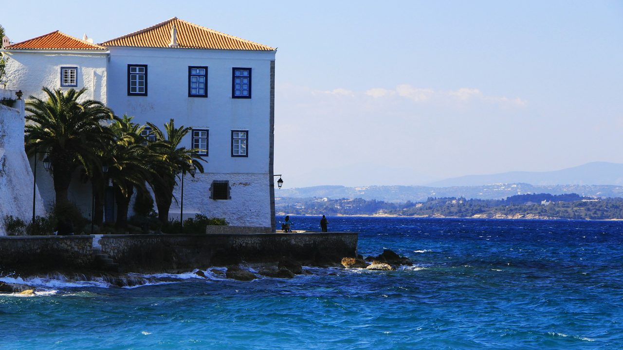 A captain's mansion and palms on the Spetses waterfront, the Peloponnese coast across the water