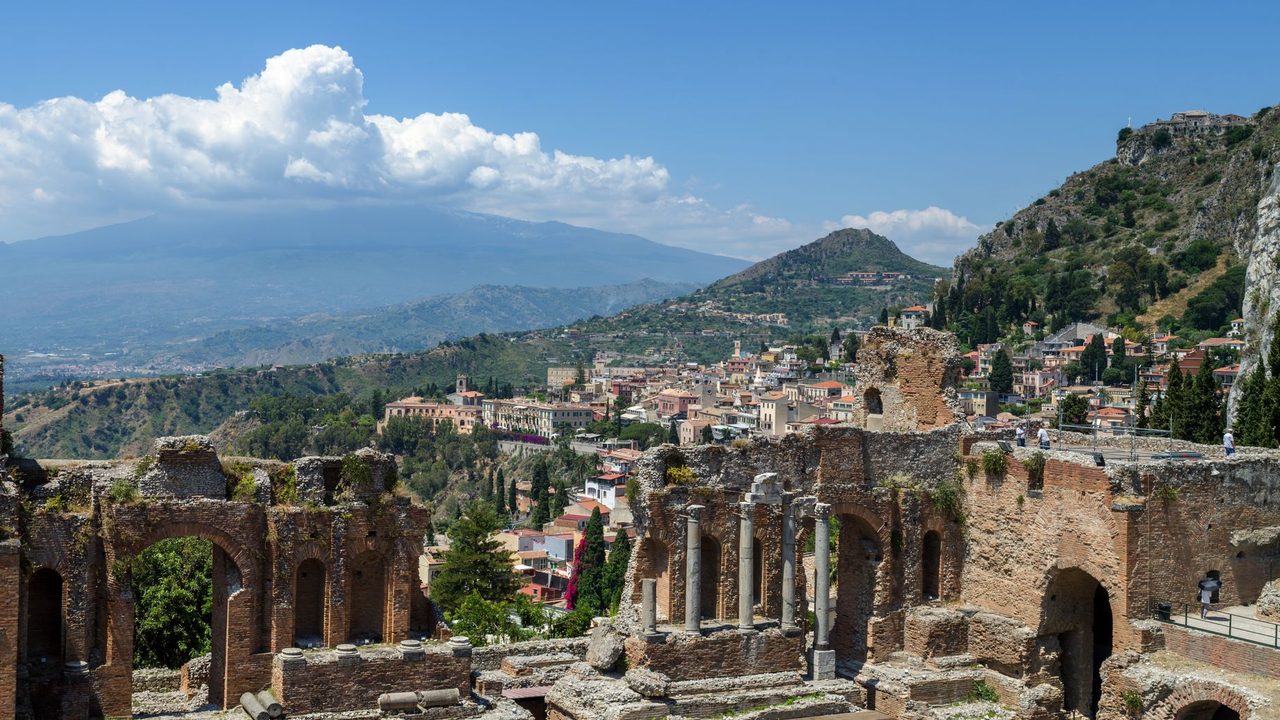 The ancient theatre of Taormina, the town and Mount Etna beyond under a summer sky