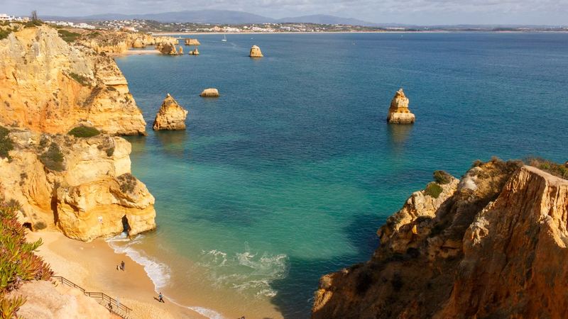 Golden cliffs and sea stacks above a turquoise cove near Lagos in the Algarve