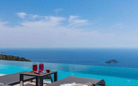 An infinity pool above the sea, two drinks on a table