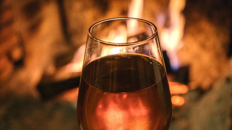 A glass glowing amber before a log fire