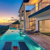 A villa with an infinity pool above the sea at sunset