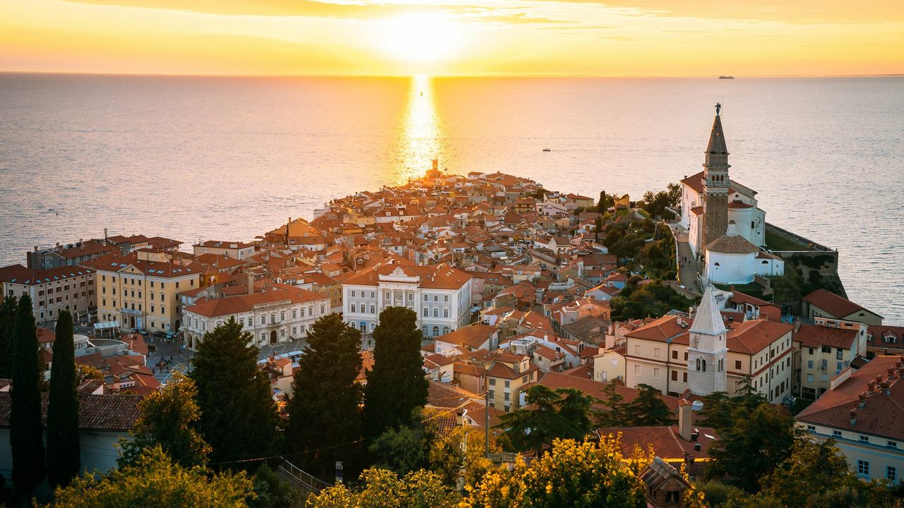 The red roofs and bell tower of Piran on its point in the Adriatic at sunset