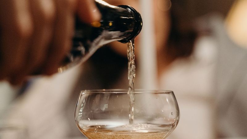 Champagne poured into a crystal coupe at a candlelit dinner table