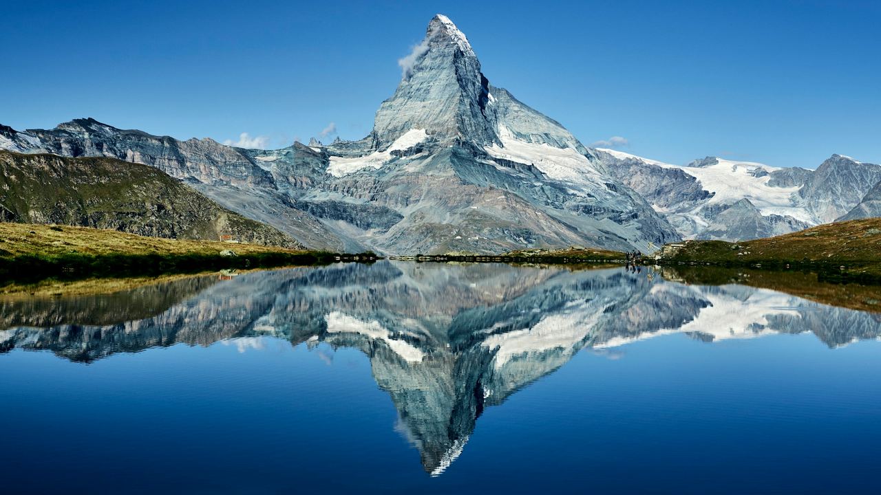 The Matterhorn reflected in a still mountain lake under a deep blue sky