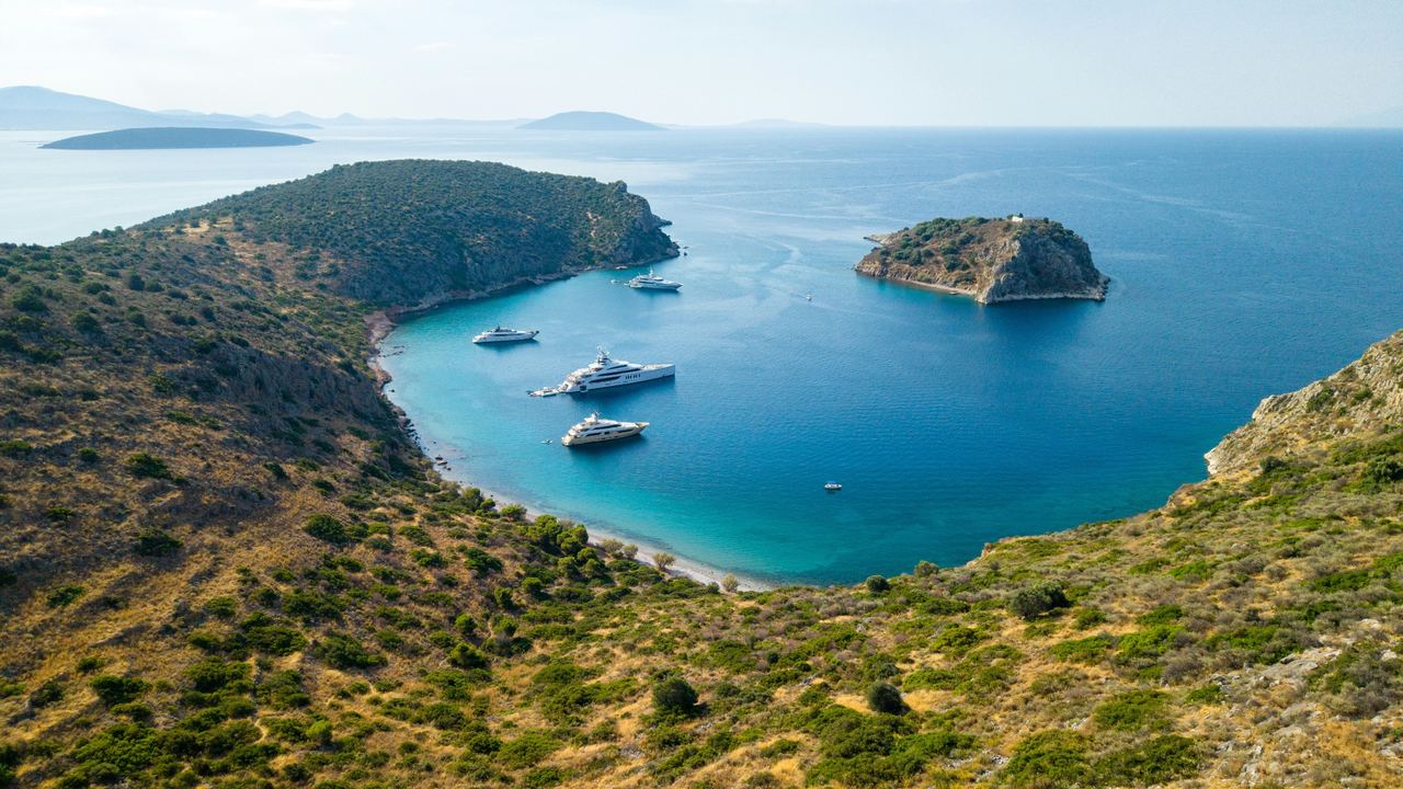 Superyachts at anchor in a turquoise bay near Tolo, Greece