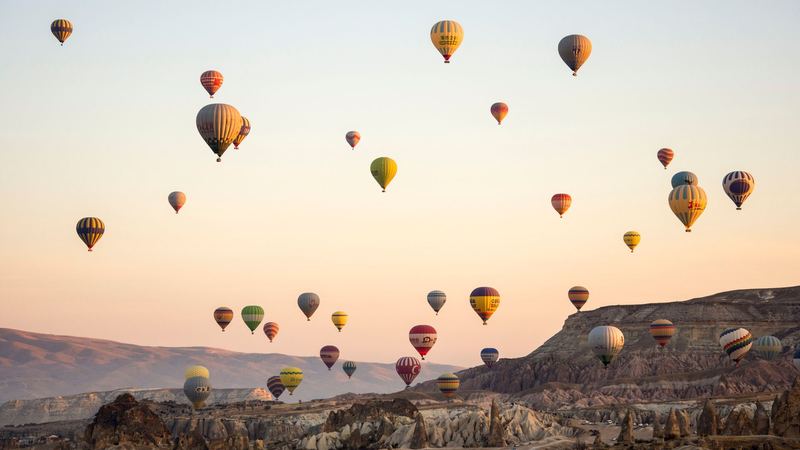 Dozens of colourful hot-air balloons rising over the rock valleys of Cappadocia at sunrise