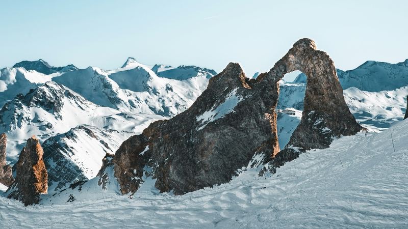The Aiguille Percée, a natural arch of rock, standing above the pistes and the snowy peaks