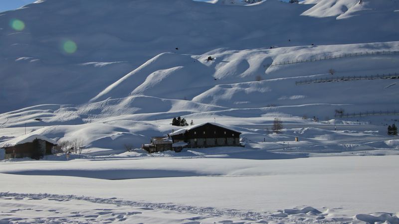A stone and timber chalet alone in deep snow below the white slopes