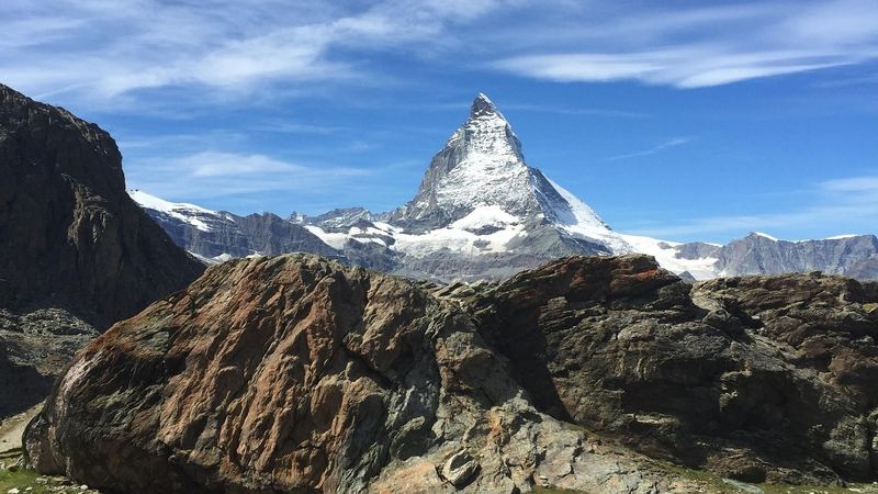 The snow-covered Matterhorn rising behind great boulders on the high path above Zermatt